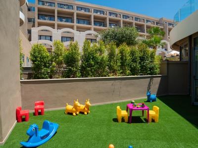 Taras na dachu z sztuczną trawą, zabawkami dla dzieci i widokiem na budynek hotelu.