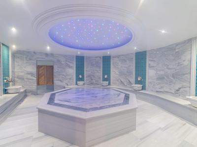 Wnętrze luksusowych łaźni tureckich z centralnym basenem i sufitem z gwiazdami.