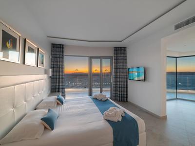 Nowoczesny pokój hotelowy z dwoma łóżkami, balkonem i widokiem na zachód słońca.