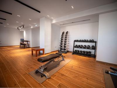 Moderner Fitnessraum mit Hanteln, Bank und Holzfußboden in einem Hotel.