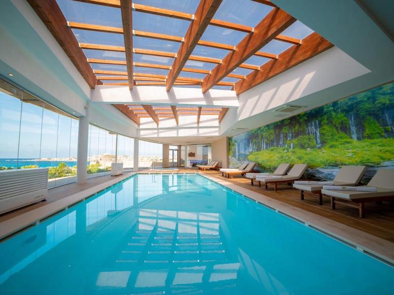 Basen kryty z dużymi oknami i światłem dziennym przez drewniany sufit kratownicowy w nowoczesnym hotelu.