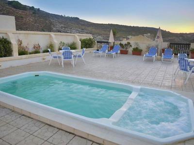 Piccola piscina all'aperto sulla terrazza con posti a sedere e vista sulle montagne al tramonto.