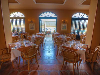 Elegantes Restaurant mit gedeckten Tischen und Blick auf das Meer durch große Fenster.