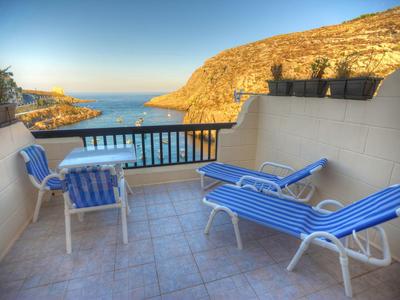 Terrasse mit zwei Liegestühlen und einem Tisch mit Stühlen mit Meerblick und Bergen