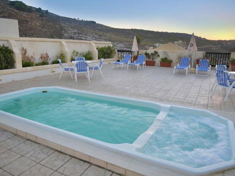 Piccola piscina all'aperto sulla terrazza con posti a sedere e vista sulle montagne al tramonto.