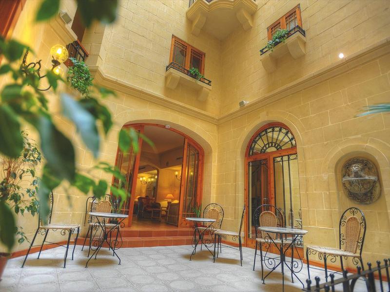 Accogliente cortile dell'hotel con tavoli, sedie e piante.