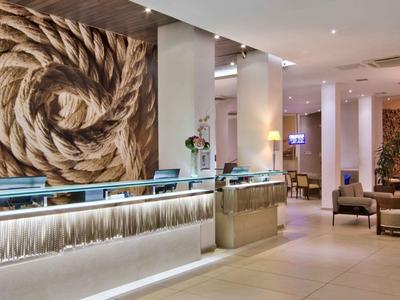 Moderner Hotelempfang mit Kunstwand, hellem Tresen und gemütlichem Sitzbereich.