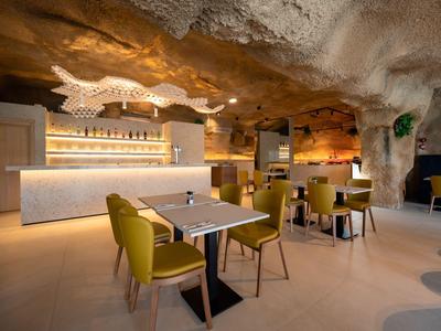 Gemütliches Restaurant in einer Höhle mit gelben Stühlen und beleuchtetem Tresen