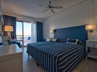 Modernes Hotelzimmer mit Doppelbett, Balkon und Meerblick bei Tageslicht.