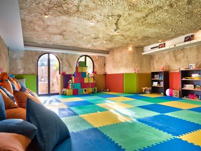 Kinderspielzimmer mit buntem Schaumstoffboden und Spielzeug in einem rustikalen Raum.
