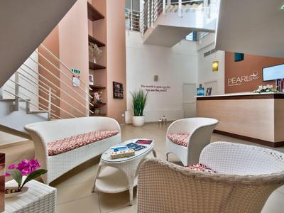 Heller, moderner Empfangsbereich mit weißem Rattanmöbel und Rezeptionstresen.