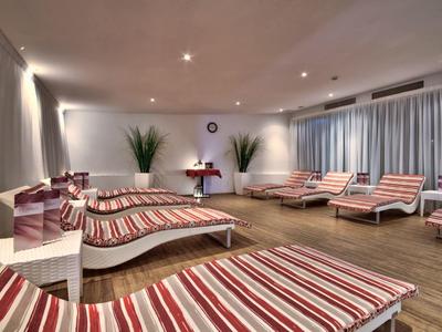 Mehrere Liegen mit rot-weiß gestreiften Polstern in einem modernen Wellness- oder Ruhebereich.