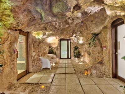 Flur mit felsartigen Wänden und Türen, dekoriert mit Pflanzen und Kerzenlicht.