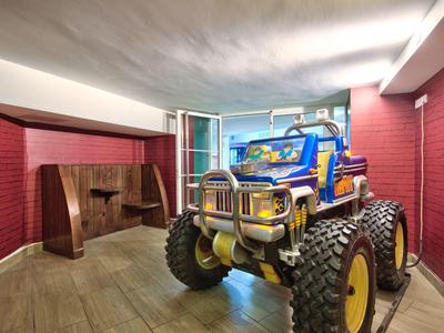 Kinderspielzeug-Geländewagen in einem hellen, modernen Raum mit roten Wänden und Holzfußboden.