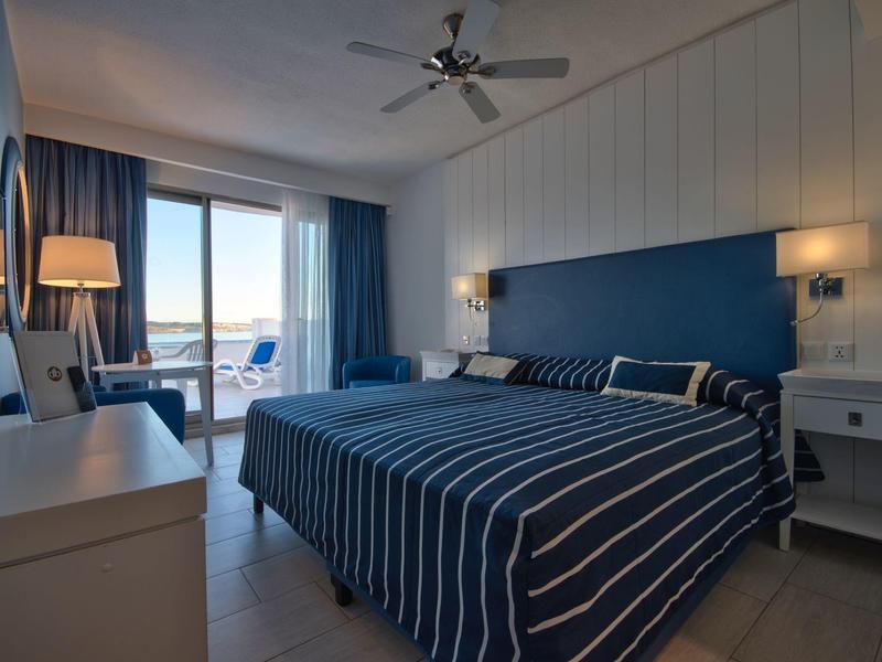 Modernes Hotelzimmer mit Doppelbett, Balkon und Meerblick bei Tageslicht.