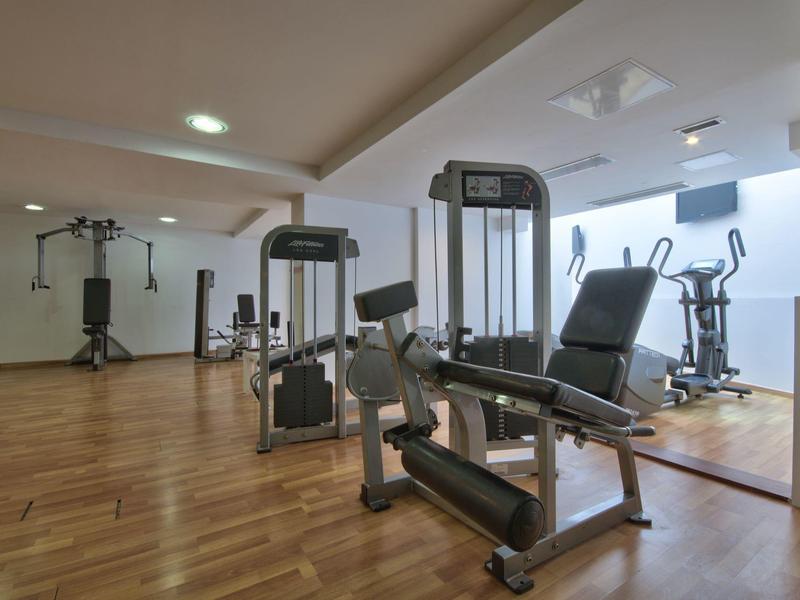 Moderner Fitnessraum mit verschiedenen Trainingsgeräten und Holzfußboden.