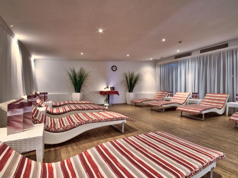 Mehrere Liegen mit rot-weiß gestreiften Polstern in einem modernen Wellness- oder Ruhebereich.