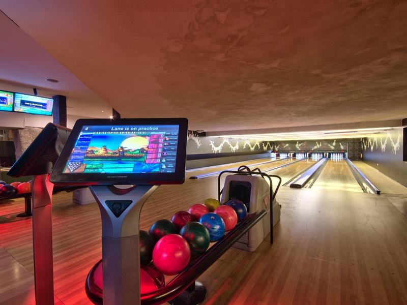Blick auf eine Bowlingbahn mit bunten Kugeln und digitaler Anzeige im Hotel