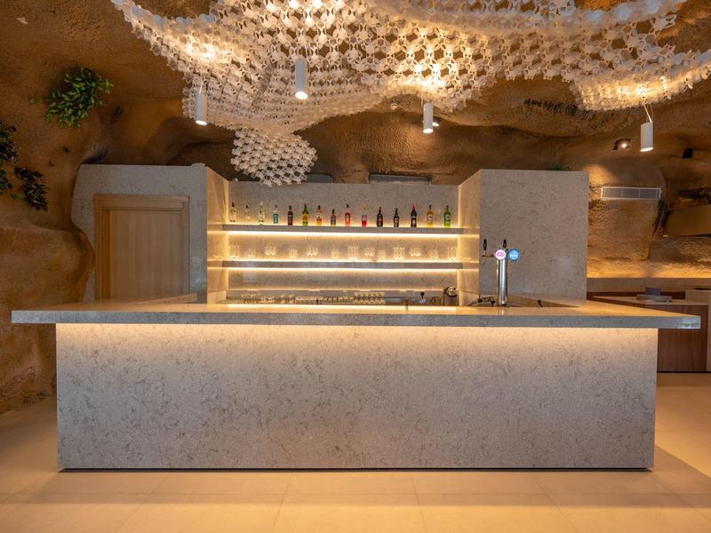 Moderner Barbereich mit steinernen Wänden und hellem, rechteckigem Tresen.