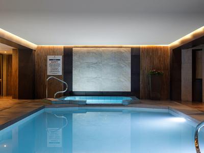 Modernes Hallenbad mit stimmungsvoller Beleuchtung und integriertem Whirlpool.