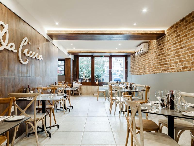 Helles, einladendes Restaurant mit Holztischen, Stühlen und Backsteinwand.