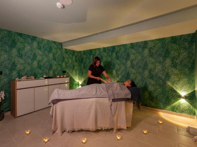 Ein entspannender Massageraum mit grünen Wänden und gedämpfter Beleuchtung.