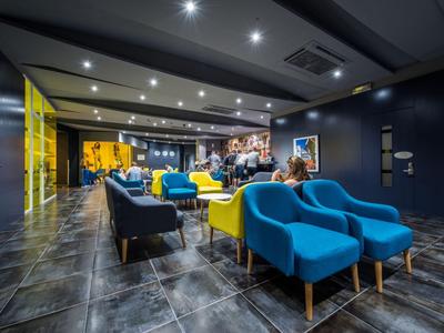 Area lounge moderna dell'hotel con poltrone colorate e illuminazione indiretta.