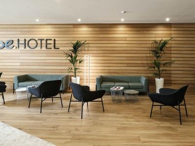Moderner Hotel-Loungebereich mit Holzwandverkleidung, Sofas, Sesseln und Pflanzen