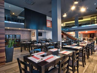 Ristorante moderno dell'hotel con mobili in legno scuro e atmosfera luminosa calda.