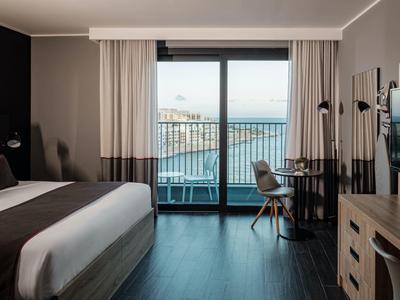 Modernes Hotelzimmer mit Meerblick durch große Glasfenster und Balkon