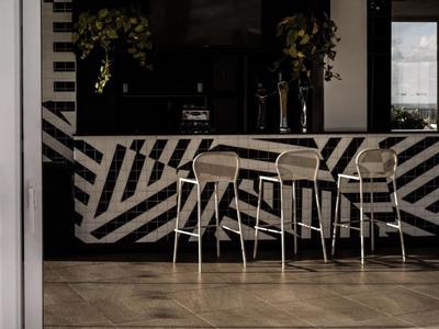 Drei hohe Stühle stehen vor einer schwarz-weißen Theke mit geometrischem Muster in einem modernen Innenraum.