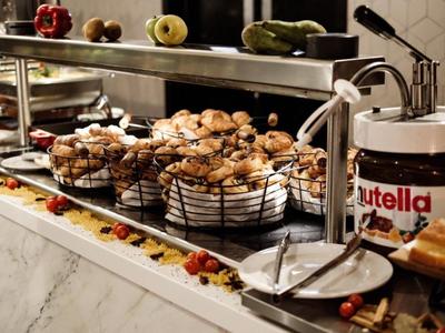 Buffet mit frischen Croissants, Gebäck und großem Nutella-Glas in einer Hotelküche.
