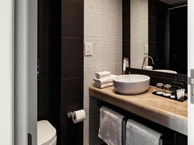 Modernes Badezimmer mit rundem Waschbecken, Holzarbeitsplatte und Handtüchern unter dem Waschbecken.