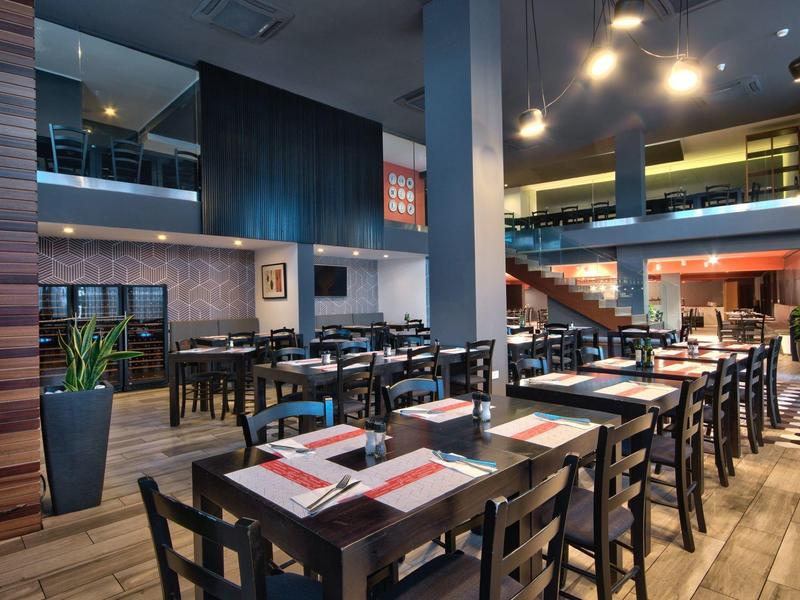 Modernes Restaurant mit Holztischen und Stühlen in hellem, einladendem Interieur.