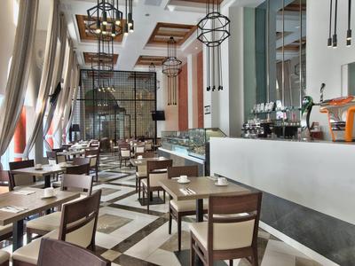 Moderní restaurace s dřevěnými stoly, židlemi a velkými okny v hotelu.