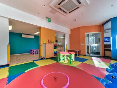 Barevná dětská herna s měkkými matracemi a malými stoly v hotelu.