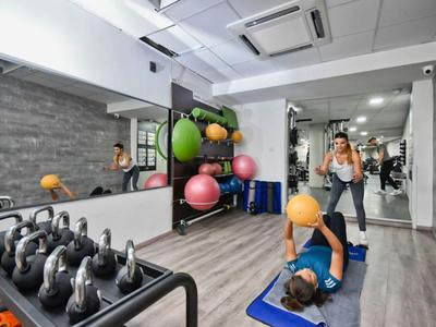 Two women exercising in a modern gym with kettlebells and exercise balls.