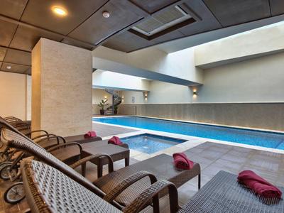 Moderní krytý bazén s několika lehátky a ručníky v elegantní wellness oblasti.