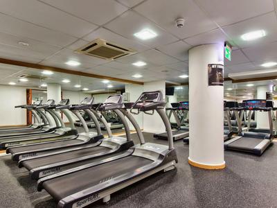 Modern gym with multiple treadmills, mirrors, and bright lighting.