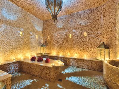 Teplá wellness oblast s mozaikovými zdmi, světlem svíček a orientálním osvětlením.