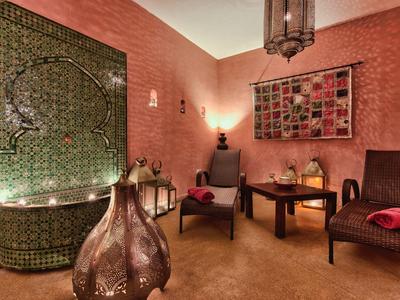 Pohodlný pokoj s orientálním dekorem, dvěma křesly, stolem a teplým osvětlením.