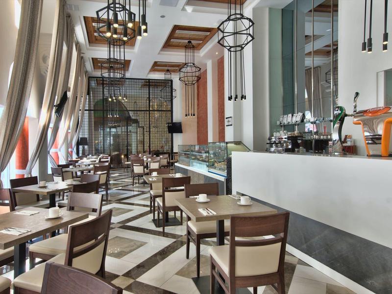 Moderní restaurace s dřevěnými stoly, židlemi a velkými okny v hotelu.