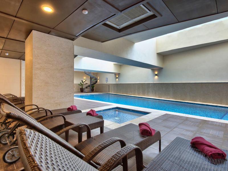 Moderní krytý bazén s několika lehátky a ručníky v elegantní wellness oblasti.