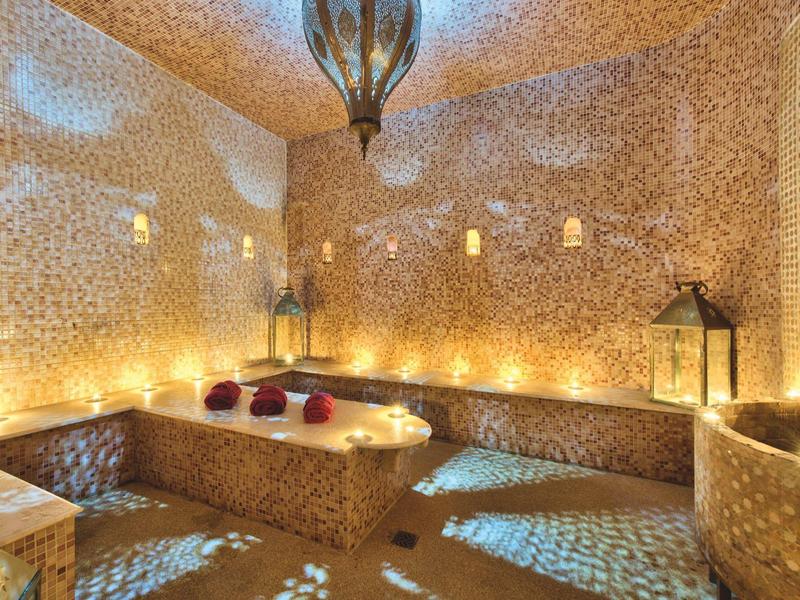 Teplá wellness oblast s mozaikovými zdmi, světlem svíček a orientálním osvětlením.