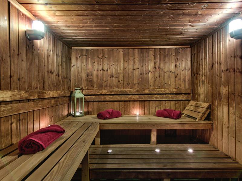 Pohodlná dřevěná sauna s červenými ručníky a osvětlením ve stylu lucerny