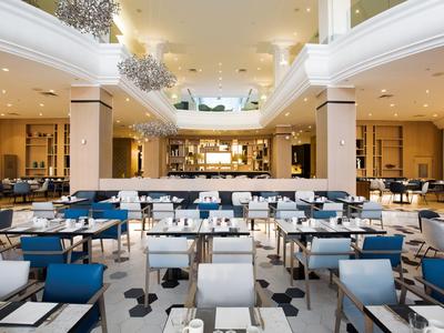 Amplio comedor moderno con sillas azules y blancas e iluminación elegante en un hotel.