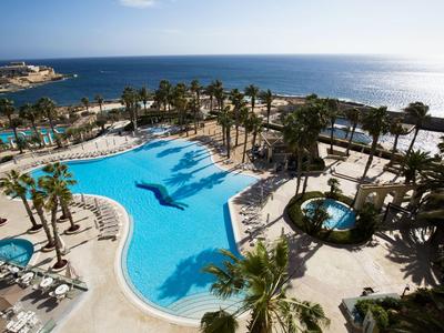 Gran piscina con palmeras y vista al océano en un resort de lujo.