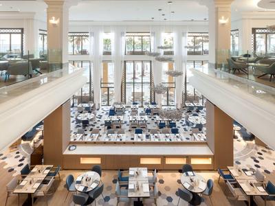 Restaurante luminoso y espacioso con decoración moderna y grandes ventanales en un hotel.