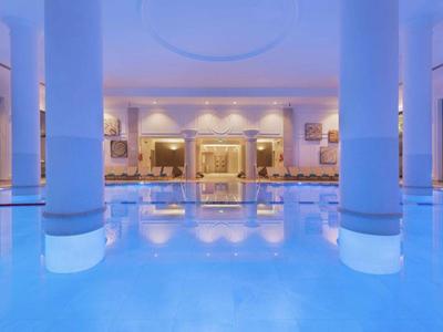 Piscina cubierta de hotel con columnas e iluminación relajante.