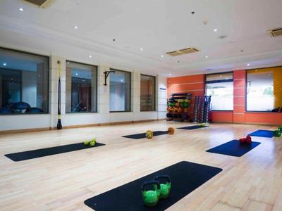 Habitación de yoga luminosa con colchonetas negras y pequeñas pesas en el suelo de madera.